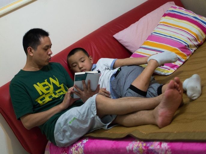 In this picture taken on August 31, 2014, seven year old Wei Yueran (R), who also has the English name Harney, listens to his father Wei Hua reading a book before his bedtime in Shanghai. After spending one year in the US, Yueran has joined the second class of the Jinqao Center Primary School in Shanghai's Pudong district. The Shanghai Education Commission recently announced the opening of 50 new public schools in the city, according to local news. AFP PHOTO / JOHANNES EISELE