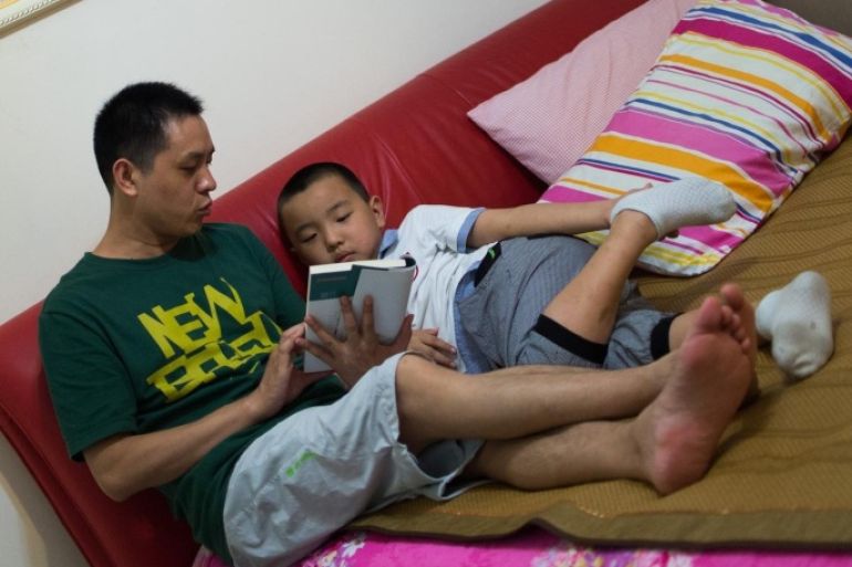 In this picture taken on August 31, 2014, seven year old Wei Yueran (R), who also has the English name Harney, listens to his father Wei Hua reading a book before his bedtime in Shanghai. After spending one year in the US, Yueran has joined the second class of the Jinqao Center Primary School in Shanghai's Pudong district. The Shanghai Education Commission recently announced the opening of 50 new public schools in the city, according to local news. AFP PHOTO / JOHANNES EISELE