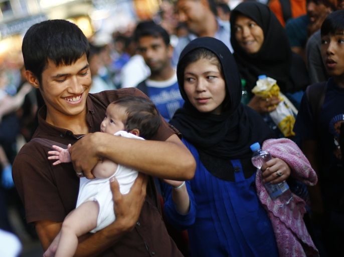 A man cradles a baby in his arms as migrants disembark from a train coming from Austria at the main station in Munich, Germany, Monday, Aug. 31, 2015. Some hundreds of migrants are arriving in Munich on Monday, after making perilous journeys into Europe. (AP Photo/Matthias Schrader)
