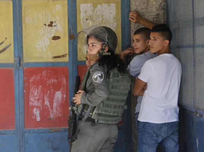 A female Israeli soldier arrests Palestinian youths after clashes which followed a demonstration in solidarity with protesters at the Al-Aqsa mosque compound in Jerusalem's Old City, at the Qalandya checkpoint near the West Bank city of Ramallah, 18 September 2015. Hundreds of people were marching in solidarity with Palestinians who clashed with Israeli security forces around the Al-Aqsa Mosque, Islam's third holiest site, in Jerusalem for several consecutive days.