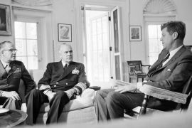 File - In this Oct. 29, 1962, file photo, President John F. Kennedy poses in the White House office with Gen. David Shoup, left, Marine Corps Commandant, and Adm. George Anderson, Chief of U.S. Naval Operations in Washington. The chiefs met with the president to review the situation in Cuba and operation of the U.S. naval blockade. As the U.S. and Russia reached the brink of nuclear war in 1962, Kennedy received top-secret intelligence from the CIA that a new warhead launcher was spotted in Cuba. That report, given to Kennedy a day before the end of the Cuban Missile Crisis, is among roughly 19,000 pages of newly declassified CIA documents from the Cold War released Wednesday, Sept. 16, 2015. (AP Photo/William J. Smith, File)