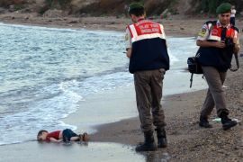 Paramilitary police officers investigate the scene before carrying the lifeless body of an unidentified migrant child, lifting it from the sea shore, near the Turkish resort of Bodrum, Turkey, early Wednesday, Sept. 2, 2015. A number of migrants are known to have died and some are still reported missing, after boats carrying them to the Greek island of Kos capsized. (AP Photo/DHA) TURKEY OUT - ONLINE OUT