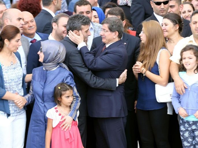 Turkeys Prime minister Ahmet Davutoglu (C) embraces Turkey's Consul in Mosul Ozturk Yilmaz as he welcomes on September 20, 2014 at the Esenboga Airport in Ankara dozens of other freed Turkish nationals hostages held by Islamist militants in northern Iraq for more than three months. Fighters from the Islamic State (IS) kidnapped 46 Turks including diplomats, children and special forces from the Turkish consulate in Mosul and 3 Iraqis on June 11 as they captured swathes of northern Iraq. AFP PHOTO / ADEM ALTAN