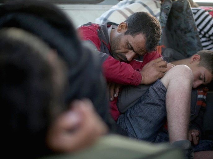 لاجئون سوريون يغطون في نوم عميق قبل أن يستقلوا القطار في محطة روسكي المجرية إلى النمسا (غيتي/الفرنسية)