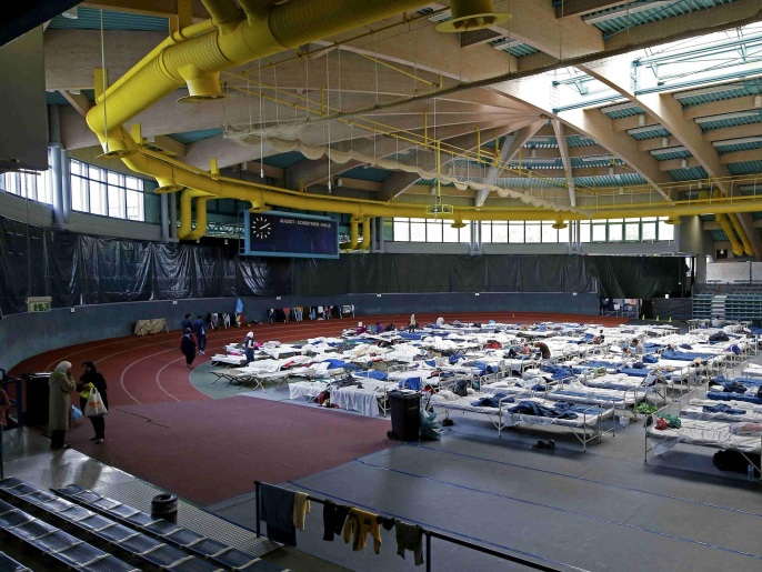 لاجئون يأخذون قسطا من الراحة في أَسرّة أُعدت لهم بإحدى الصالات الرياضية بمدينة هناو الألمانية (رويترز)