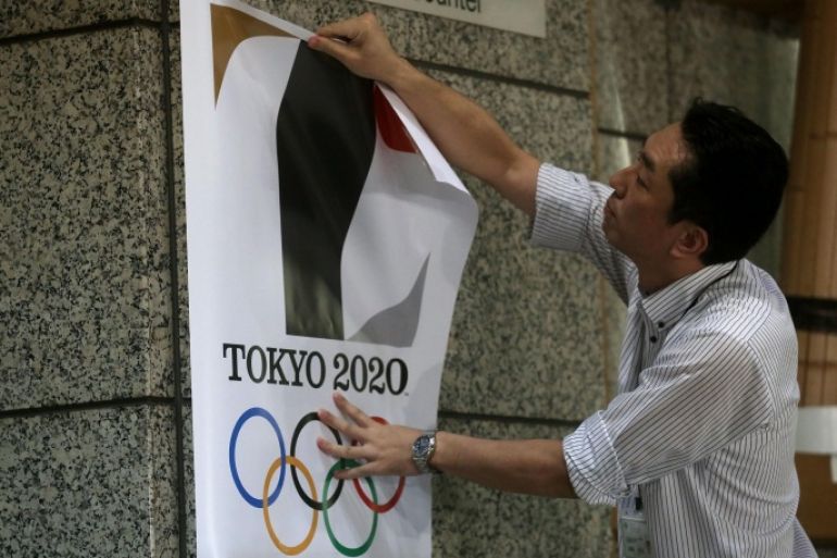 TOKYO, JAPAN - SEPTEMBER 01: An employee removes a Tokyo 2020 Olympic poster showing the copied logo design hung at the entrance of the Tokyo Metropolitan Government Office building during an event staged for the media on September 1, 2015 in Tokyo, Japan. The 2020 Tokyo Olympics organizing committee announced after an emergency meeting that it will cease using the logo after it was found to have been plagiarized by designer Kenjiro Sano.
