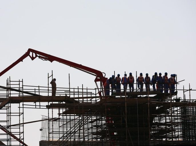 MUSCAT, OMAN - FEBRUARY 17: Construction workers stop the watch the race pass on stage one of the 2015 Tour of Oman, a 161km road stage from Bayt Al Naman Castle to Al Wutayyah on February 17, 2015 in Muscat, Oman.