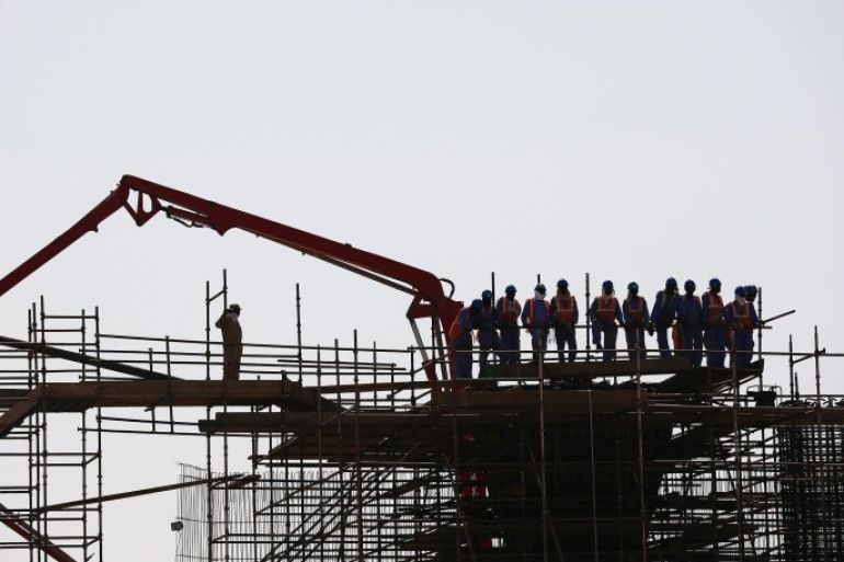 MUSCAT, OMAN - FEBRUARY 17: Construction workers stop the watch the race pass on stage one of the 2015 Tour of Oman, a 161km road stage from Bayt Al Naman Castle to Al Wutayyah on February 17, 2015 in Muscat, Oman.