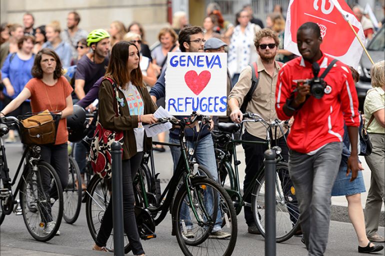 epa04927220 People taking part in a demonstration in support of migrants hold placards with slogans welcoming refugees at the place Neuve, in Geneva, Switzerland, 12 September 2015. EPA