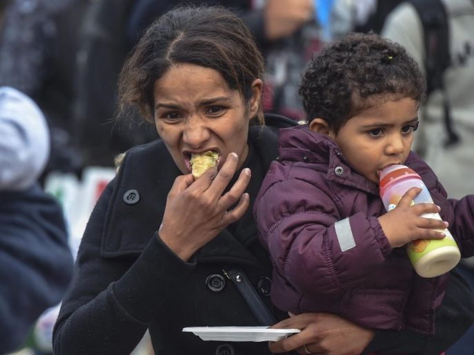 A migrant mother holds her child and eats traditional sweets, delivered by volunteers for celebration of Eid al Adha, at the registration camp near the city of Gevgelija, The Former Yugoslav Republic of Macedonia, 24 September 2015. Thousands of migrants continue to arrive in Macedonia on their way to EU countries. After Hungary sealed its borders, migrants began taking an alternative route to Western Europe via Croatia.
