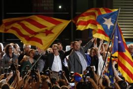 "Estelada" or pro independence flags are waved in front of the President of Democratic Convergence of Catalonia Artur Mas, left and Oriol Junquieras, president of the Esquerra Republicana de Catalunya party in front of supporters in Barcelona, Spain, Sunday Sept. 27, 2015. Voters in Catalonia participated in an election Sunday that could propel the northeastern region toward independence from the rest of Spain or quell secessionism for years. An exit poll predicts that pro-independence parties in Spain's Catalonia region are likely to win a majority of seats in the regional parliament, but it's unclear whether they would be able to come together to push together on a plan to secede from Spain. (AP Photo/Manu Fernandez)