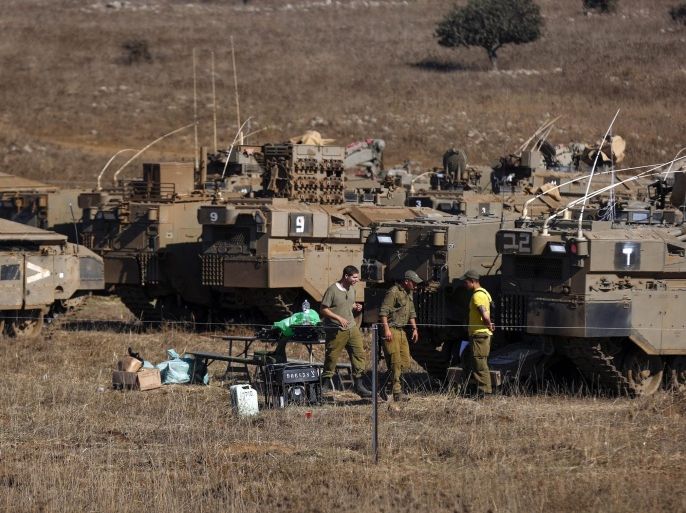 Israeli soldiers walking next to their Armored Personnel Carrier (APCs) unite deployed in the Golan Heights, near the Israeli-Syrian border 21 August 2015. Israeli Army spokesmen confirmed targeting 14 Syrian military posts in the Syrian part of the Golan Heights and the killing of four militants responsible for firing rockets toward north Israel.