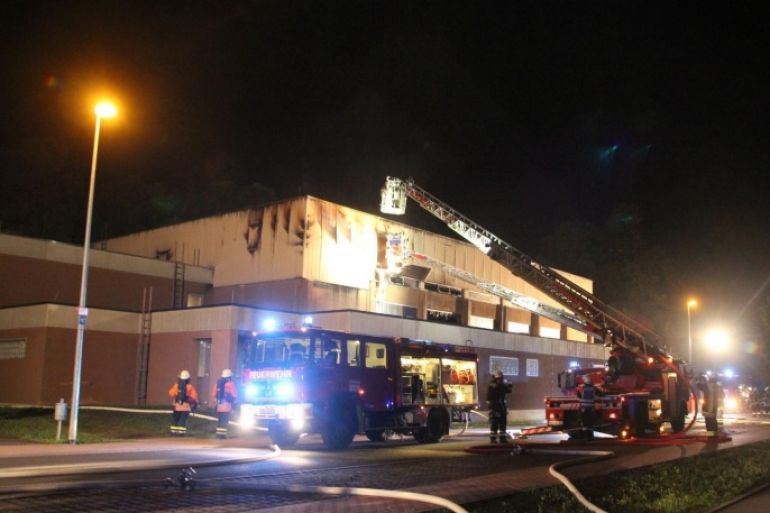 Firefighters extinguish a fire at a building planned to serve as a emergency refugee shelter in Wertheim, Germany, 20 September 2015. Some 330 bed were already installed at the sports hall.