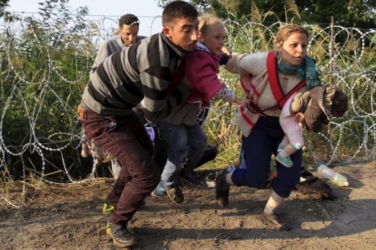 Syrian migrants run after crossing under a fence as they enter Hungary, at the border with Serbia, near Roszke, August 27, 2015. Hungary made plans on Wednesday to reinforce its southern border with helicopters, mounted police and dogs, and was also considering using the army as record numbers of migrants, many of them Syrian refugees, passed through coils of razor-wire into Europe. REUTERS/Bernadett Szabo