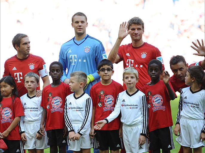 (L-r) Bayern Munich's defender Philipp Lahm, Manuel Neuer and Thomas Mueller stand with migrant children (in red) prior to the German first division Bundesliga football match FC Bayern Munich v FC Augsburg, in Munich, on September 12, 2015. AFP PHOTO / DPA / ANDANDREAS GEBERT ===GERMANY OUT RESTRICTIONS: DURING MATCH TIME: DFL RULES TO LIMIT THE ONLINE USAGE TO 15 PICTURES PER MATCH AND FORBID IMAGE SEQUENCES TO SIMULATE VIDEO. == RESTRICTED TO EDITORIAL USE ==