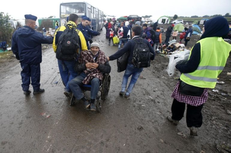 Migrants pull the wheelchair of disabled man in front of a makeshift camp for asylum seekers near Roszke, southern Hungary, Friday, Sept. 11, 2015. EU officials and human rights groups say they've been disappointed by the animosity toward asylum-seekers in countries from which hundreds of thousands of people fled communist dictatorships just decades ago. (AP Photo/Darko Vojinovic)