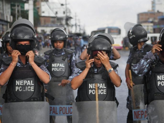 Nepalese policemen stand guard as activists of Nepal's Madhesi group protest against the new constitution outside the Constituent Assembly hall in Kathmandu, Nepal, Saturday, Sept. 19, 2015. Various ethnic groups and Madhesi political parties are protesting against the new constitution saying it discriminates or denies rights to their respective communities and is a conspiracy against ethnicity-based federalism. Nepal’s President Ram Baran Yadav will announce the new constitution on Sept. 20 in a ceremony expected to be attended by members of parliament, cabinet members, members of constitutional bodies, high ranking Nepal’s security forces and members of the diplomatic community. (AP Photo/Niranjan Shrestha)