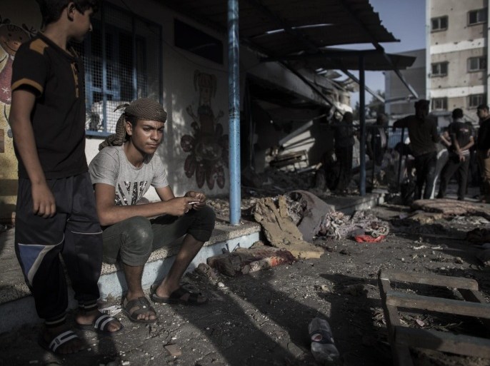 Young Palestinians sit next to a destroyed classroom at a UN school in Jabalia, northern Gaza Strip, 30 July 2014. According to medics at least 17, many of whom were internally displaced Palestinians who sought shelter in the school run by the United Nations Relief and Works Agency, were killed by shelling from Israeli Defense Forces.