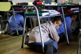 Students take cover under their desk inside a school during an earthquake drill in Santiago, November 13, 2014. Around one million people, which included students, teachers and parents, took part on Thursday in a drill that simulated a fictitious earthquake of a magnitude of 8.8 on the Richter scale, according to organizers. REUTERS/Ivan Alvarado (CHILE - Tags: SOCIETY DISASTER EDUCATION TPX IMAGES OF THE DAY)
