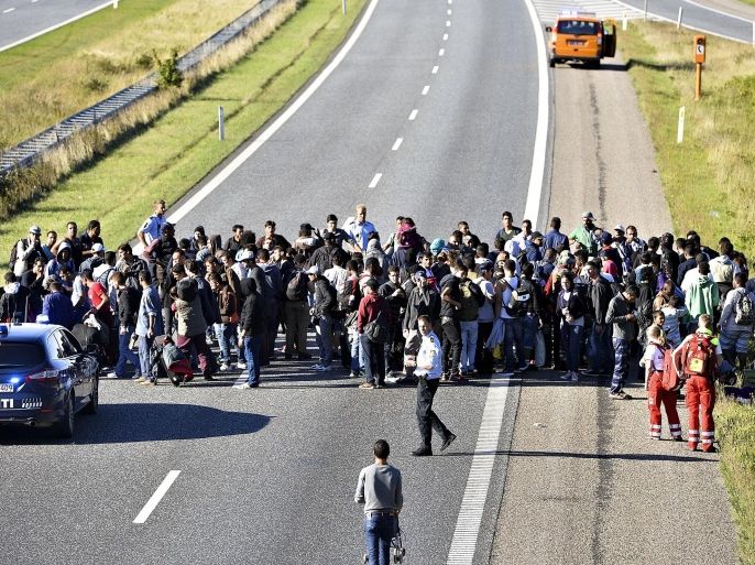 A group of refugees and migrants who were walking north stand on the highway in southern Denmark on Wednesday, Sept. 9, 2015. The migrants have crossed the border from Germany, and after staying at a local school, they say they are now making their way to Sweden, to seek asylum. (Ernst van Norde/Polfoto via AP) DENMARK OUT
