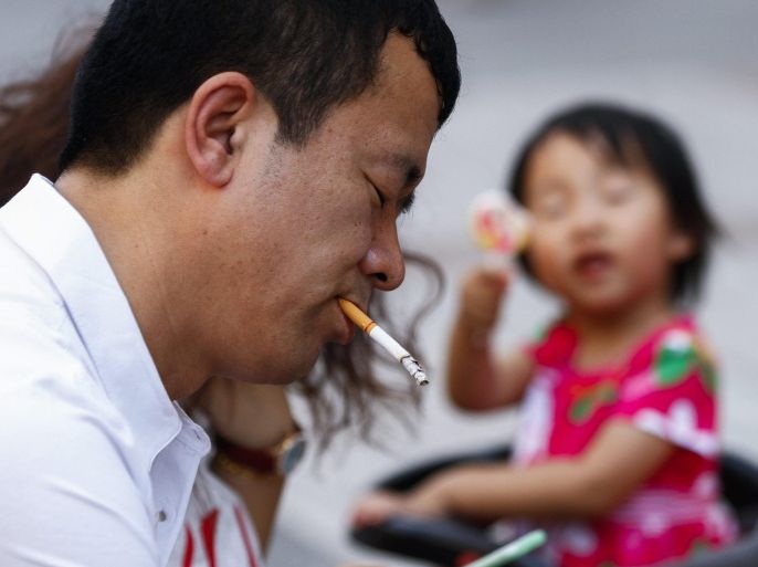 A Chinese man smokes a cigarette next to a baby in a stroller at a shopping district of Beijing, China, 31 May 2015. Following World No Tobacco Day on 31 May, Beijing is set to implement a new smoking ban starting 01 June in efforts to curb smoking in public and work places and indoor areas of commercial establishments.