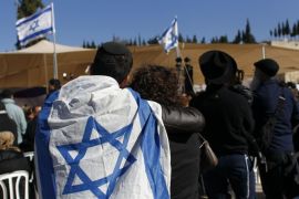 A mourner with an Israeli flag draped over his shoulder attends the joint funeral of Yohan Cohen, Yoav Hattab, Philippe Braham and Francois-Michel Saada, victims of Friday's attack on a Paris grocery, in Jersualem January 13, 2015. Four French Jews killed in the attack on a kosher supermarket in Paris were buried in Jerusalem on Tuesday before thousands of French and Israeli mourners, with Prime Minister Benjamin Netanyahu saying they had been returned to their "true home".REUTERS/Ronen Zvulun (JERUSALEM - Tags: CIVIL UNREST POLITICS OBITUARY)