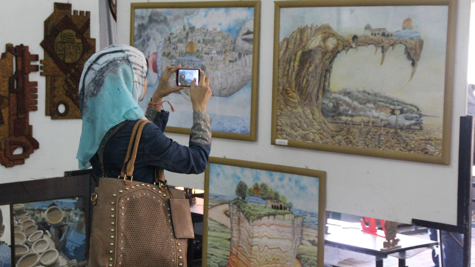 ‪فتاة تلتقط صورا تذكارية لبعض اللوحات الفنية‬ (الجزيرة)