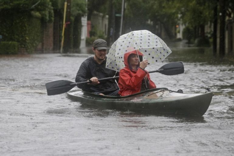 Paul Banker, left, paddles a kayak and his wife Wink Banker, right, takes photos on a flooded street in Charleston, S.C., Saturday, Oct. 3, 2015. A flash flood warning was in effect in parts of South Carolina, where authorities shut down the Charleston peninsula to motorists. (AP Photo/Chuck Burton)