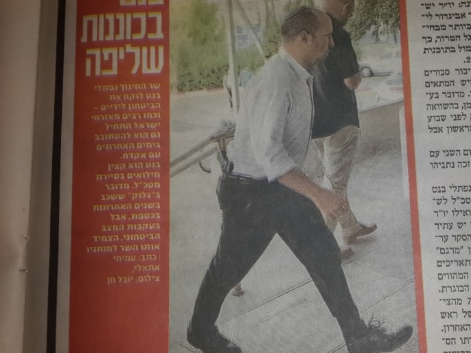 ‪وزير التعليم الإسرائيلي نفتالي بينيت يتجول حاملا مسدسا‬ (الجزيرة)