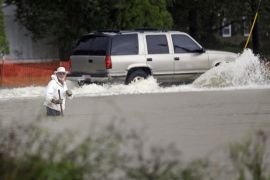 Floodwaters rise as a vehicle and a man navigate flooded streets in Florence, S.C., Sunday, Oct. 4, 2015. The rainstorm drenching the East Coast brought more misery Sunday to South Carolina, cutting power to thousands, forcing hundreds of water rescues and closing scores of roads because of floodwaters. (AP Photo/Gerry Broome)