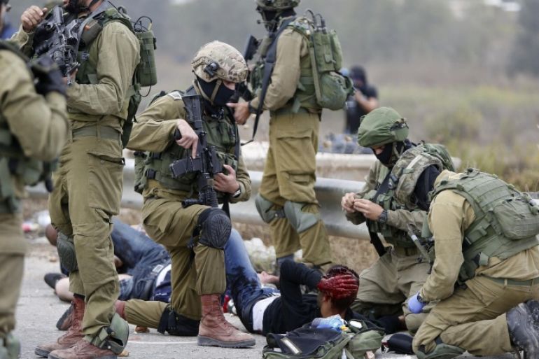 Israeli soldiers treat Palestinian demonstrators wounded during clashes between Palestinians and Israeli military forces, near Ramallah, West Bank, Wednesday, Oct. 7, 2015. Israel's prime minister says he is calling off a planned trip to Germany because of a wave of violence between Israelis and Palestinians. A statement from Benjamin Netanyahu's office Wednesday said the Israeli leader would not depart for the two-day visit so that he could "closely monitor the situation." (AP Photo/Majdi Mohammed)