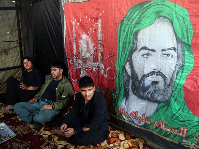 Shiite Muslim men sit near a drawing of Hazrat-i Imam Hussein, the grandson of Prophet Muhammad, during a procession to mark Ashoura in Kabul, Afghanistan, Wednesday, Oct. 21, 2015. Ashoura is a Shiite Muslim commemoration marking the death of Hussein, the Prophet Muhammad's grandson, at the Battle of Karbala in present-day Iraq. (AP Photo/Massoud Hossaini)