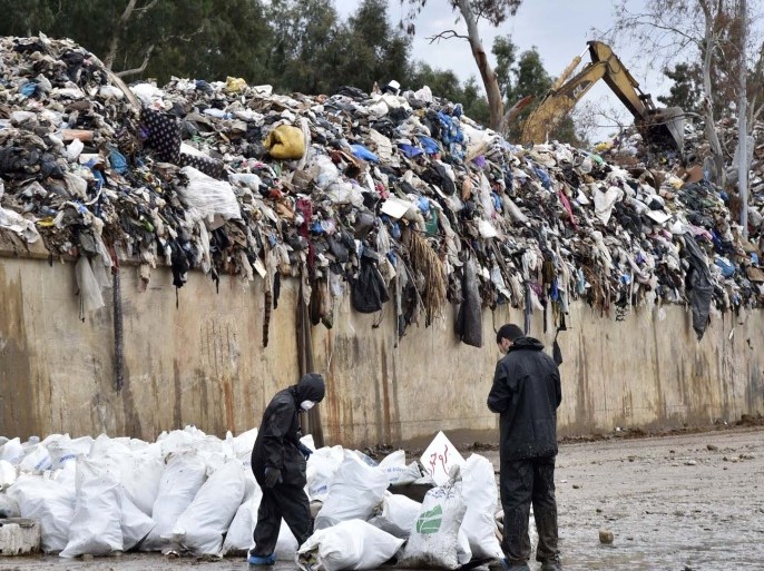 عاملان نضافة يجمعان القمامة بجوار احد مكبات النفاية