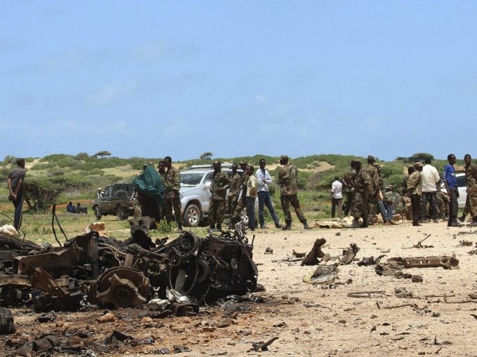 Jubaland forces and Somali residents stand near the site of a suicide car bomb attack near a military training base in the port town Kismayu, south of capital Mogadishu August 22, 2015. A suicide car bomb was rammed into a military training base in the Somali port city of Kismayu on Saturday, killing "many soldiers", officials said. Residents said they heard a loud blast followed by gunfire. Military officials said the attack was launched as soldiers were lining up for training. REUTERS/Abdiqani Hassan