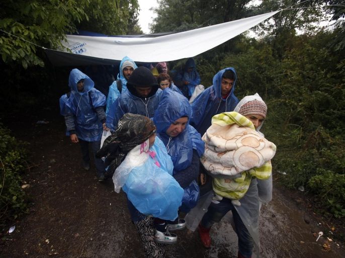 A group of migrants head to cross a border line between Serbia and Croatia, near the village of Berkasovo, about 100 km west from Belgrade, Serbia, Tuesday, Sept. 29, 2015. Asylum seekers are slogging through rain and mud-caked roads in Croatia, as autumnal conditions worsen on their journeys to seek sanctuary in richer European countries. (AP Photo/Darko Vojinovic)