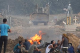 Palestinian protesters take cover as an Israeli army bulldozer is seen during clashes with Israeli troops near the border between Israel and Central Gaza Strip October 20, 2015. A three-week-old uprising by knife-wielding, Internet-generation teenagers against Israelis has left 80-year-old Palestinian President Mahmoud Abbas looking like yesterday's man, unable either to oppose the violence or openly endorse it. REUTERS/Ibraheem Abu Mustafa
