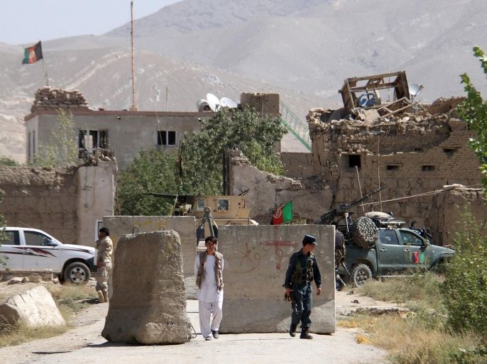 An Afghan policeman (R) walks outside a prison building after an attack in Ghazni province, Afghanistan September 14, 2015. Taliban insurgents stormed a mud fort being used as a prison in Afghanistan on Monday, killing police and releasing more than 400 inmates, and then attacked troops rushing to help, officials said. REUTERS/Stringer