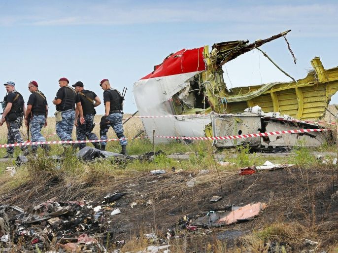 (FILE) Armed rebel soldiers pass a big piece of debris at the main crash site of the Boeing 777 Malaysia Airlines flight MH17, which crashed during flying over the eastern Ukraine region, near Grabovo, some 100 km east of Donetsk, Ukraine, 20 July 2014. The Dutch Safety Board, on 13 October 2015, will report the results of its investigation into the downing of Malaysia Airlines flight MH17 over Ukraine which killed all 298 people on board. The report is to answer whether the Boeing jet was struck by a Russia-made ground-to-air Buk missile. The aeroplane was en route from Amsterdam to Kuala Lumpur at the time of the July 17, 2014, crash. The Netherlands has taken the lead in the investigation, since most of the dead were Dutch nationals.