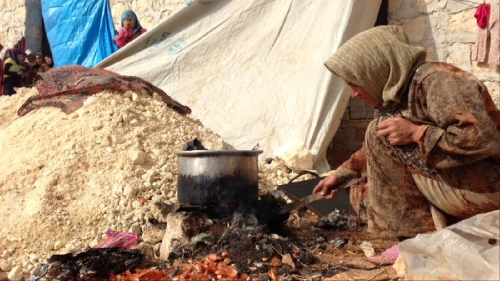 سورية تعد الطعام في ريف حلب الجنوبي على نار أشعلتها من مخلفات بلاستيكية (الجزيرة نت)
