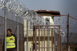 A security guard walks along a fence topped with barbed and razor wire in a facility for a detention of foreigners in the village of Drahonice, western Czech Republic, October 2, 2015. The Refugee Facilities Administration of the Interior Ministry will open this detention centre on October 5, 2015, to house incoming migrants. REUTERS/David W Cerny