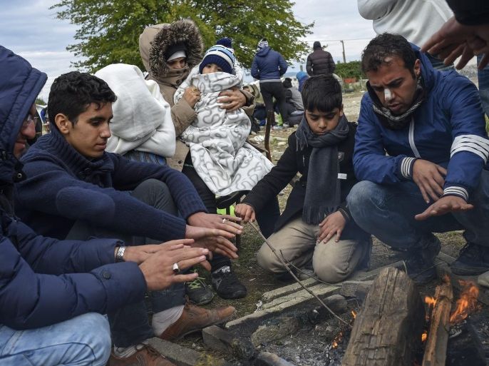 Migrants keep themselves warm around a fire waiting to enter the registration camp after they cross the border between Greece and Macedonia, near the city of Gevgelija, The Former Yugoslav Republic of Macedonia on 21 October 2015. Thousands of migrants continue to arrive in Macedonia on their way to EU countries. Europe is grappling with the biggest migrant influx since World War II, and more than half of those arriving are estimated to be from Syria.