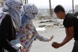 Masked Palestinian girls give stones to protesters during clashes at Howara checkpoint near the West Bank city of Nablus, 12 October 2015. A Palestinian was shot dead in the Old City of Jerusalem n 12 October after trying to stab Israeli border policemen in the Old City of Jerusalem. The death brought to 13 the number of Palestinians from the West Bank killed in an outburst of violence since 01 October, the ministry said. At least half of them were shot dead after or during attempts to stab Israeli bystanders. Four Israelis have been stabbed to death.
