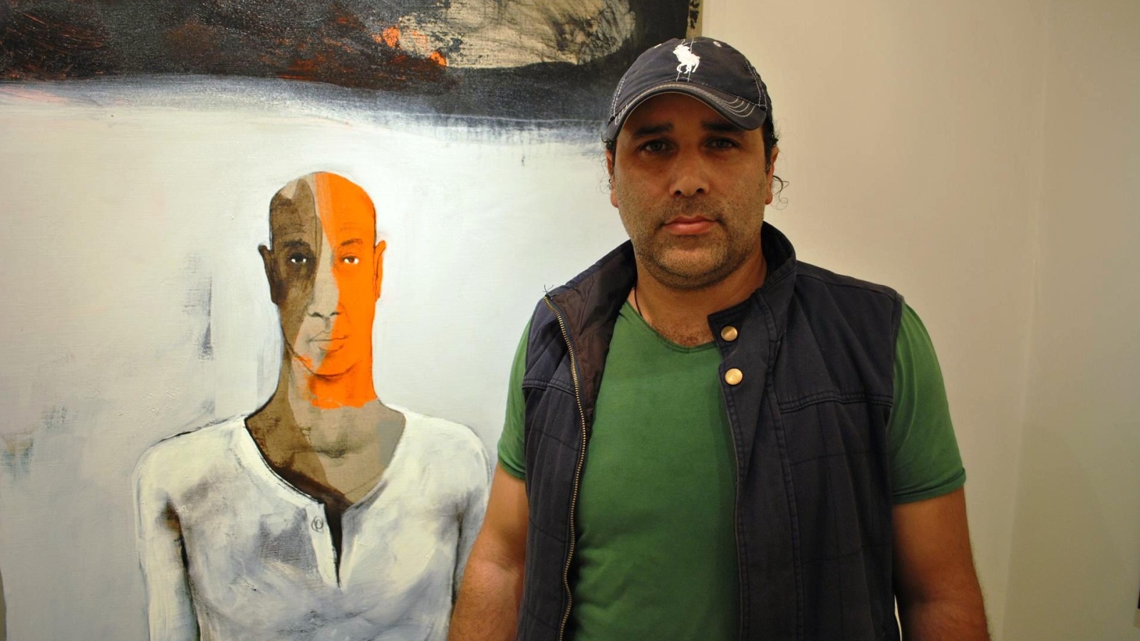 ‪التشكيلي كمال أبو حلاوة أمام لوحة لبهرام حاجو‬ (الجزيرة)