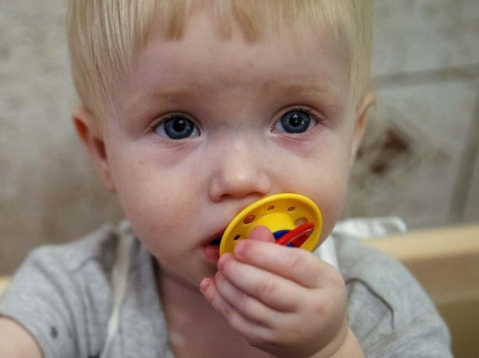 A child, whose name is written on arm, sucks on a pacifier in a crib in an orphanage in Kramatorsk August 30, 2014. 76 children from orphanages in Donetsk and Makeyevka in eastern Ukraine were sent to Kramatorsk due to fighting between the Ukrainian army and pro-Russian separatists. REUTERS/Gleb Garanich (UKRAINE - Tags: CONFLICT CIVIL UNREST SOCIETY)
