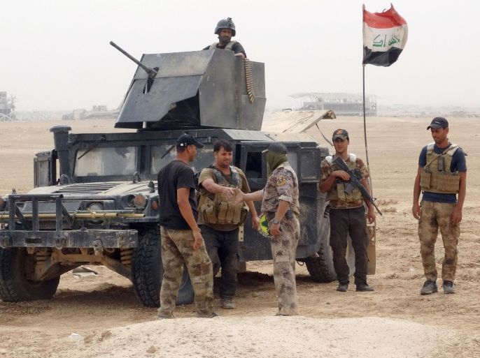 In this Tuesday, Oct. 6, 2015, photo, Iraqi soldiers congratulate each other after regaining control of the Ramadi Stadium, in the background, and the neighboring al-Bugleeb area. Iraqi security forces, backed by Sunni and Shiite volunteers supported by U.S.-led coalition airstrikes against Islamic State group advanced their position after heavy clashes in the western suburbs of Ramadi, Anbar province, Iraq. (AP Photo)