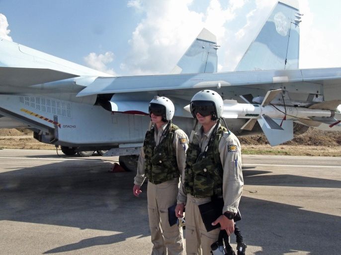 In this photo taken on Monday, Oct. 5, 2015, Russian pilots stand outside their Su-30 jet fighter, armed with air-to-air missiles, before a take off at Hmeimim airbase in Syria. NATO also strongly criticized the Russian air campaign in Syria that began Wednesday. (AP Photo/Dmitry Steshin, Komsomolskaya Pravda, Photo via AP)