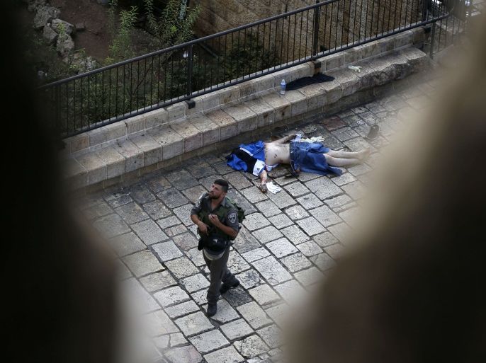 An Israeli border guard walks past the body of a Palestinian who was shot dead by Israeli security forces after he stabbed two police officers on October 10, 2015 outside the Old City in east Jerusalem, in the second such attack in the same area. The attack took place by the Damascus Gate, metres (yards) away from where a Palestinian teen stabbed two Jews before being shot dead by police earlier in the day.