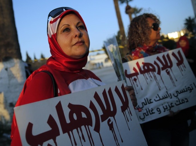 A woman holds a placard reading: "No to Terrorism" as she demonstrates in front of the National Bardo Museum a day after gunmen attacked the museum and killed scores of people in Tunis, Tunisia, Thursday, March 19, 2015. The Islamic State group issued a statement Thursday claiming responsibility for the deadly attack on Tunisia's national museum that killed scores of people, mostly tourists. (AP Photo/Christophe Ena)