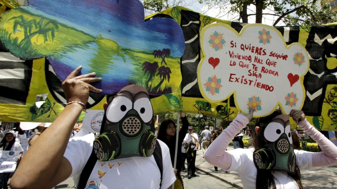 Activists wearing gas mask replicas hold placards during in a rally held the day before the start of the Paris Climate Change Conference (COP21), in La Paz, Bolivia, November 29, 2015. The placard reads, "If you want to keep living, your surroundings have to continue to exist". REUTERS/David Mercado