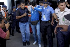 Policemen escort one of five Syrian men detained at Toncontin international airport in Tegucigalpa, Honduras, November 18, 2015. Honduran authorities have detained five Syrian nationals who were trying to reach the United States using stolen Greek passports, but there are no signs of any links to last week's attacks in Paris, police said. The Syrian men were held late on Tuesday in the Honduran capital, Tegucigalpa, on arrival from Costa Rica, and had been planning to head to the border with neighboring Guatemala. The passports had been doctored to replace the photographs with those of the Syrians, police said. REUTERS/Stringer EDITORIAL USE ONLY. NO RESALES. NO ARCHIVE.